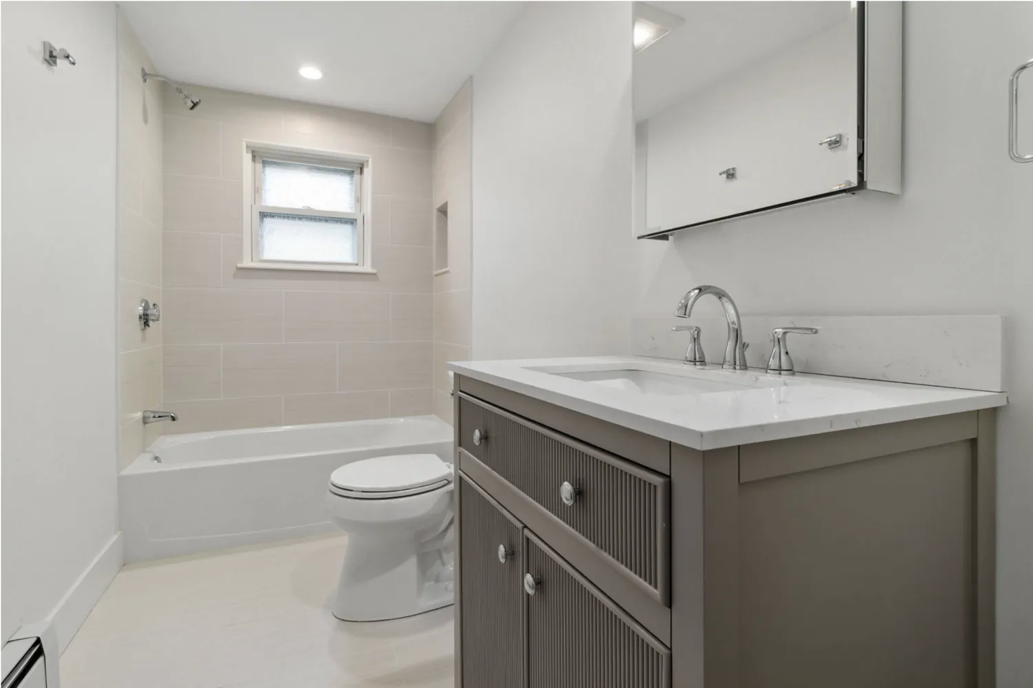 Bathroom renovation with tiled tub surround and quartz vanity
