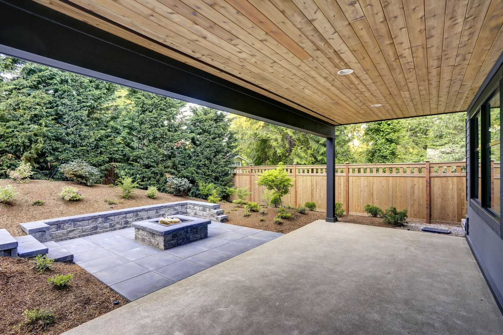 Concrete patio with stone fire pit and covered outdoor living area