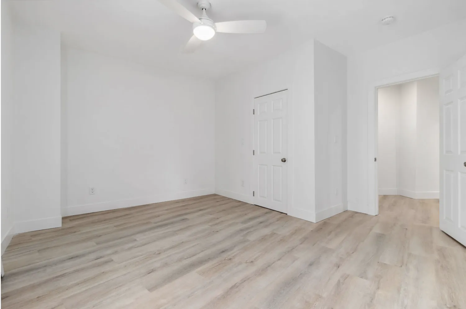 Renovated bedroom with new plank flooring, trim, and lighting