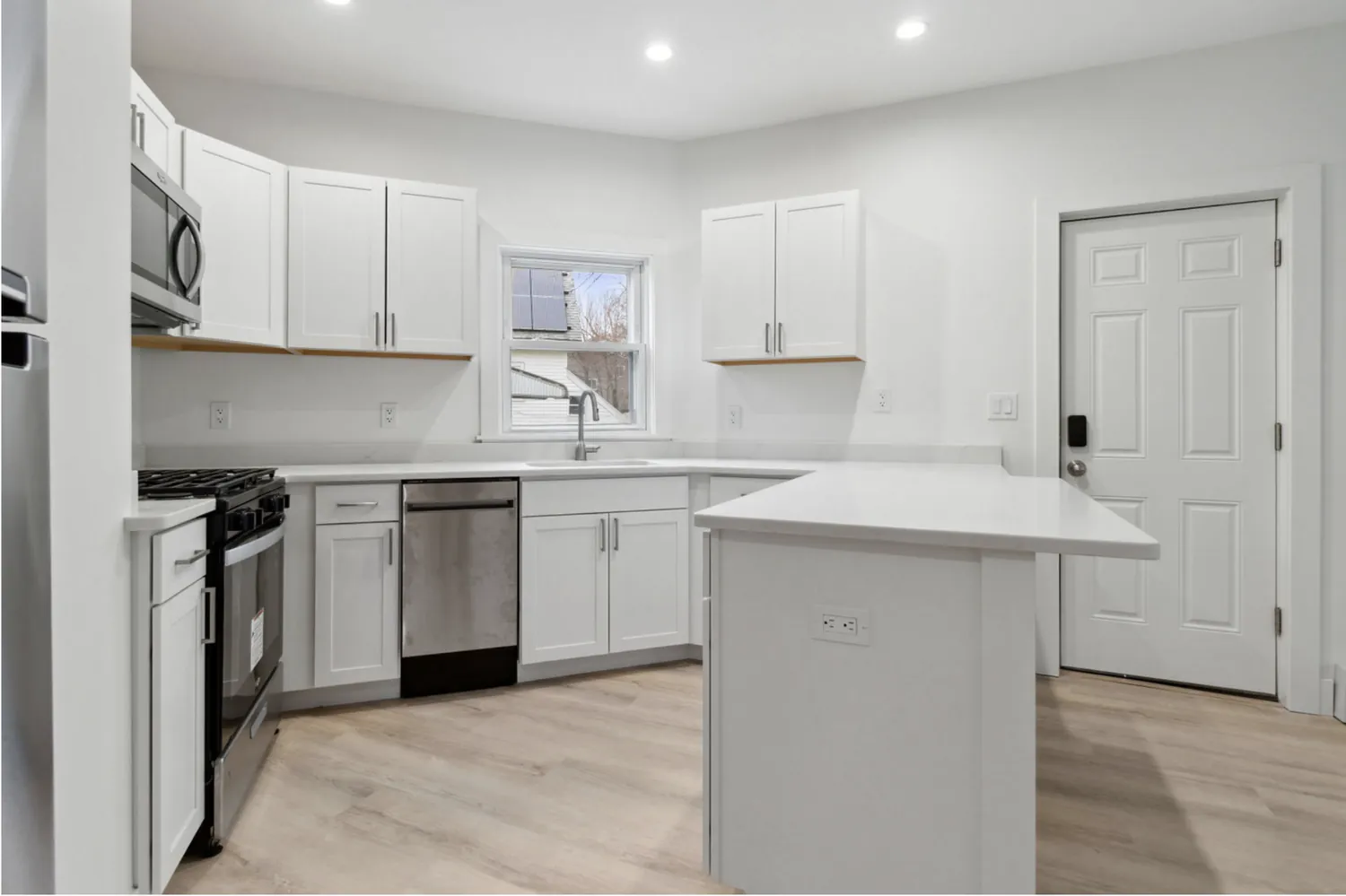 Finished kitchen remodel with white shaker cabinets, quartz counters, and island