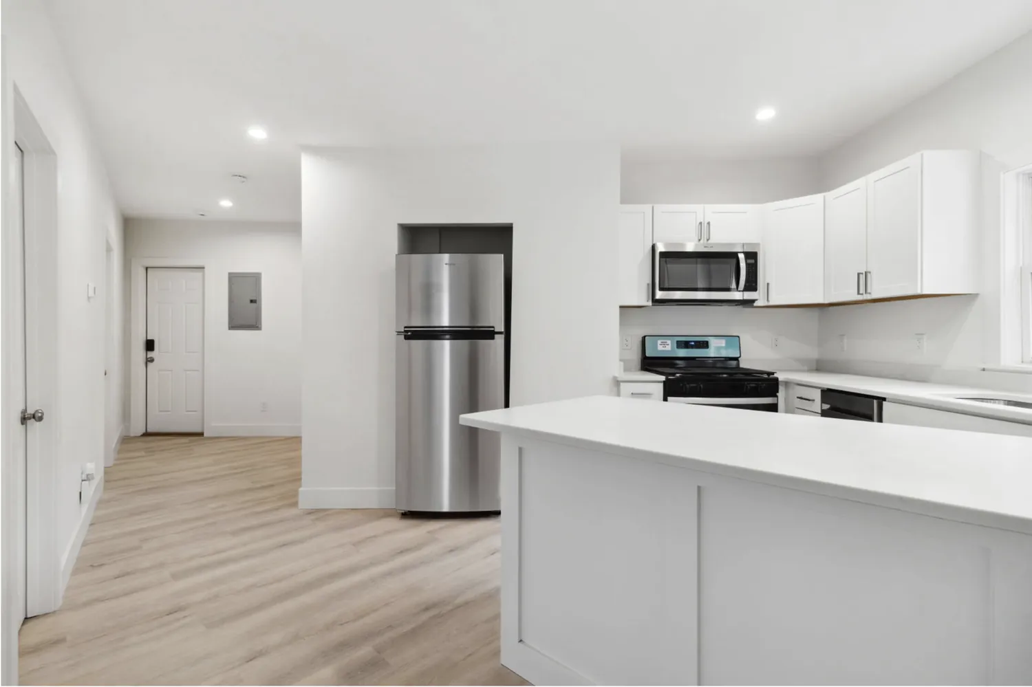 Open kitchen renovation with island, stainless appliances, and new flooring