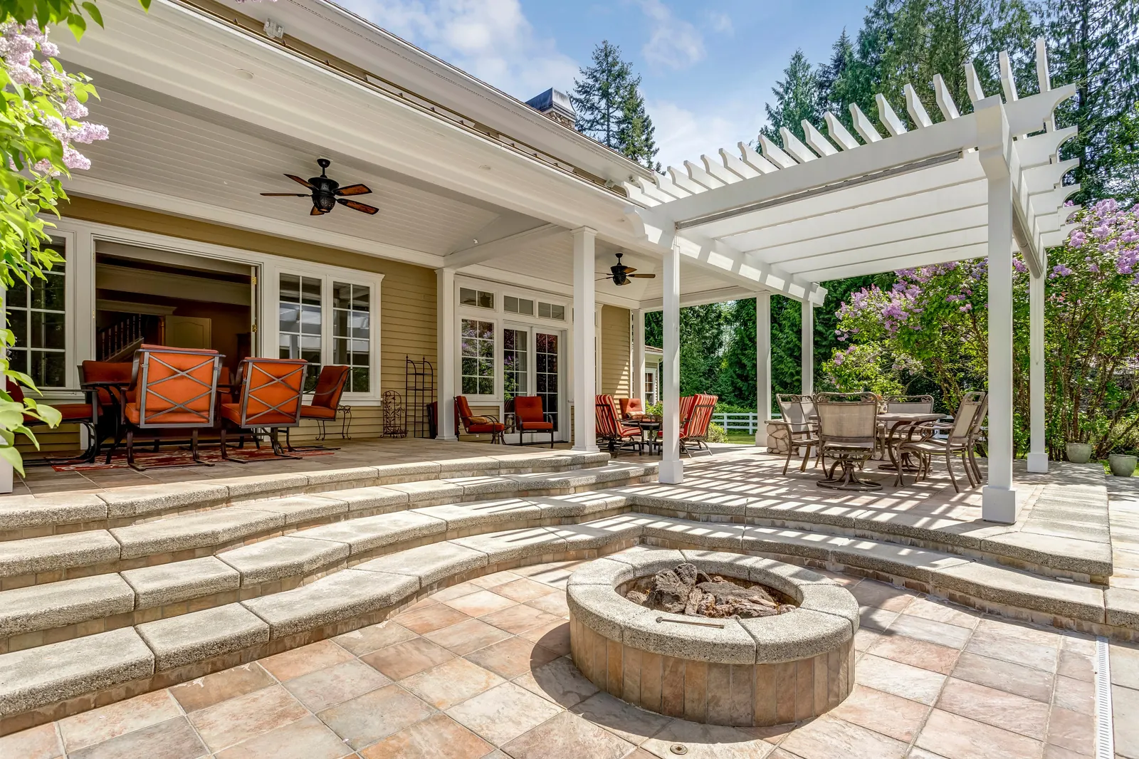 White pergola over patio with fire pit and outdoor dining space